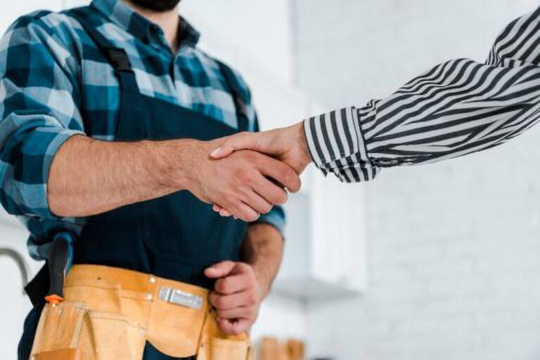 Un plombier serrant la main d’un client, illustrant la confiance et la satisfaction du service.